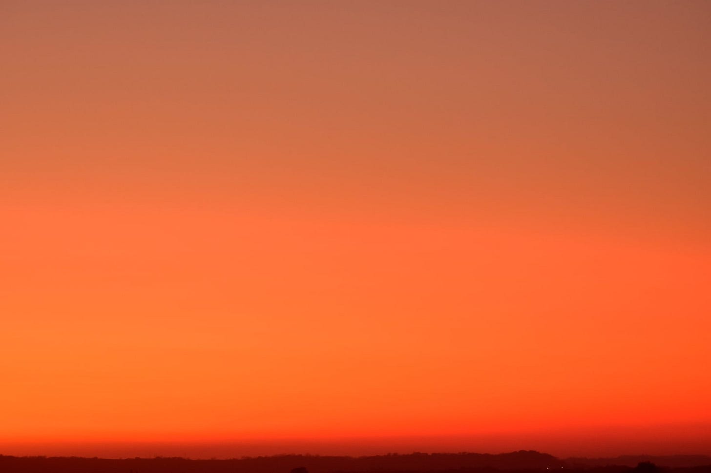 Picture of sunset with the top being a dull orange and the color getting brighter as you move down to the bottom of the photo.