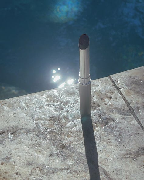 "Product shot of Clinique Black Honey lipstick, placed against a poolside background to highlight the aesthetic appeal of the cult-favorite makeup item.