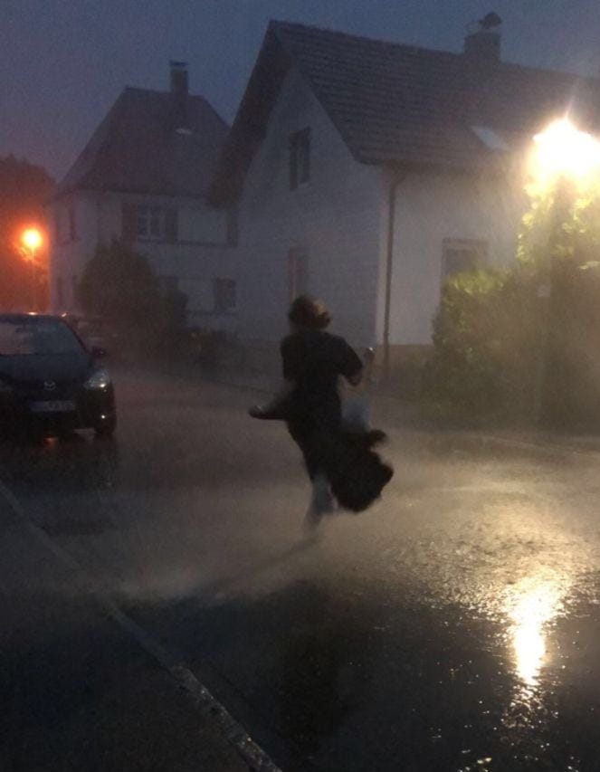 This may contain: a person jumping in the air on a street at night with cars and buildings behind them