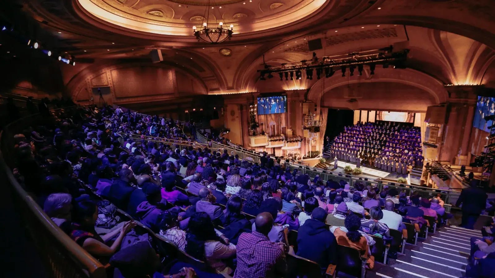 Brooklyn Tabernacle seen from the balcony, the auditorium full under a domed ceiling and the choir massed in purple robes on the stage