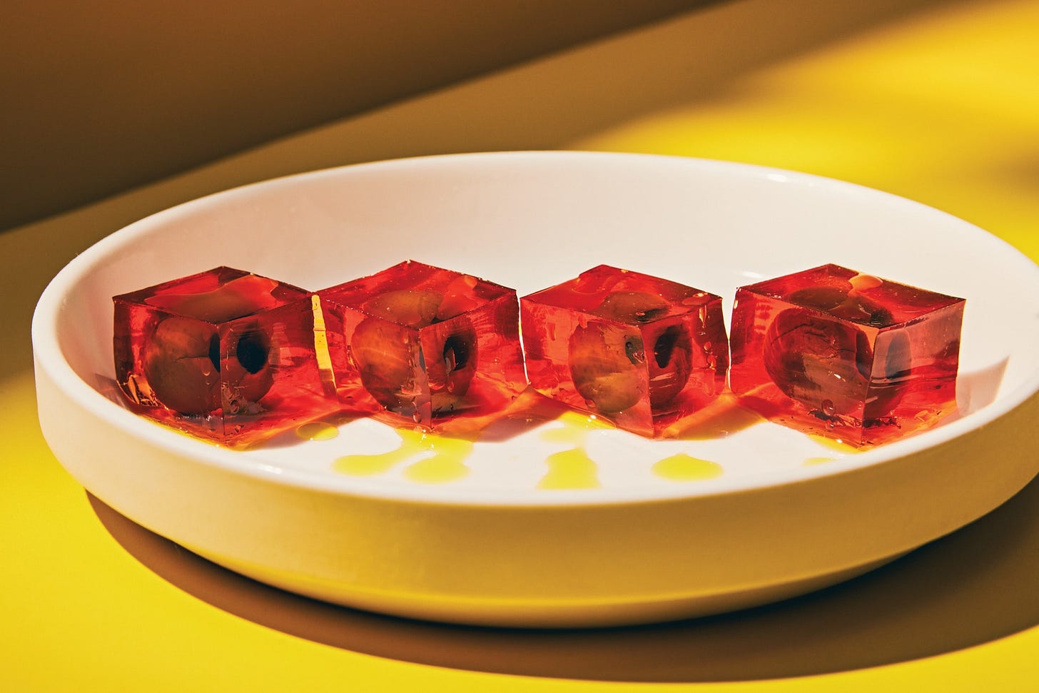 A plate of Negroni jello cubes filled with olives. A plate of Negroni jello cubes filled with olives.