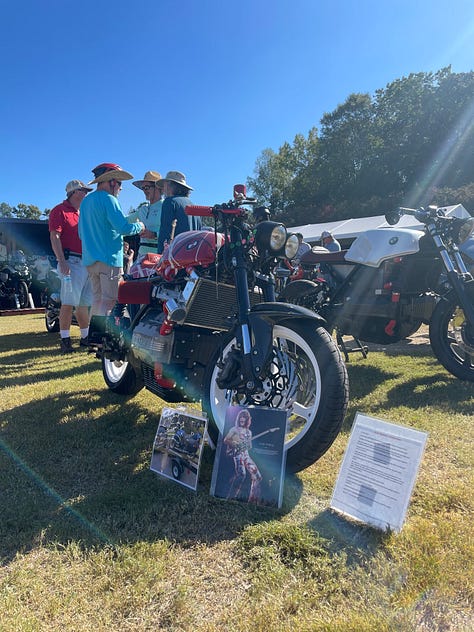 an artist doing a large live sketch of a concept bike; the race track; vintage bikes, and a cigar