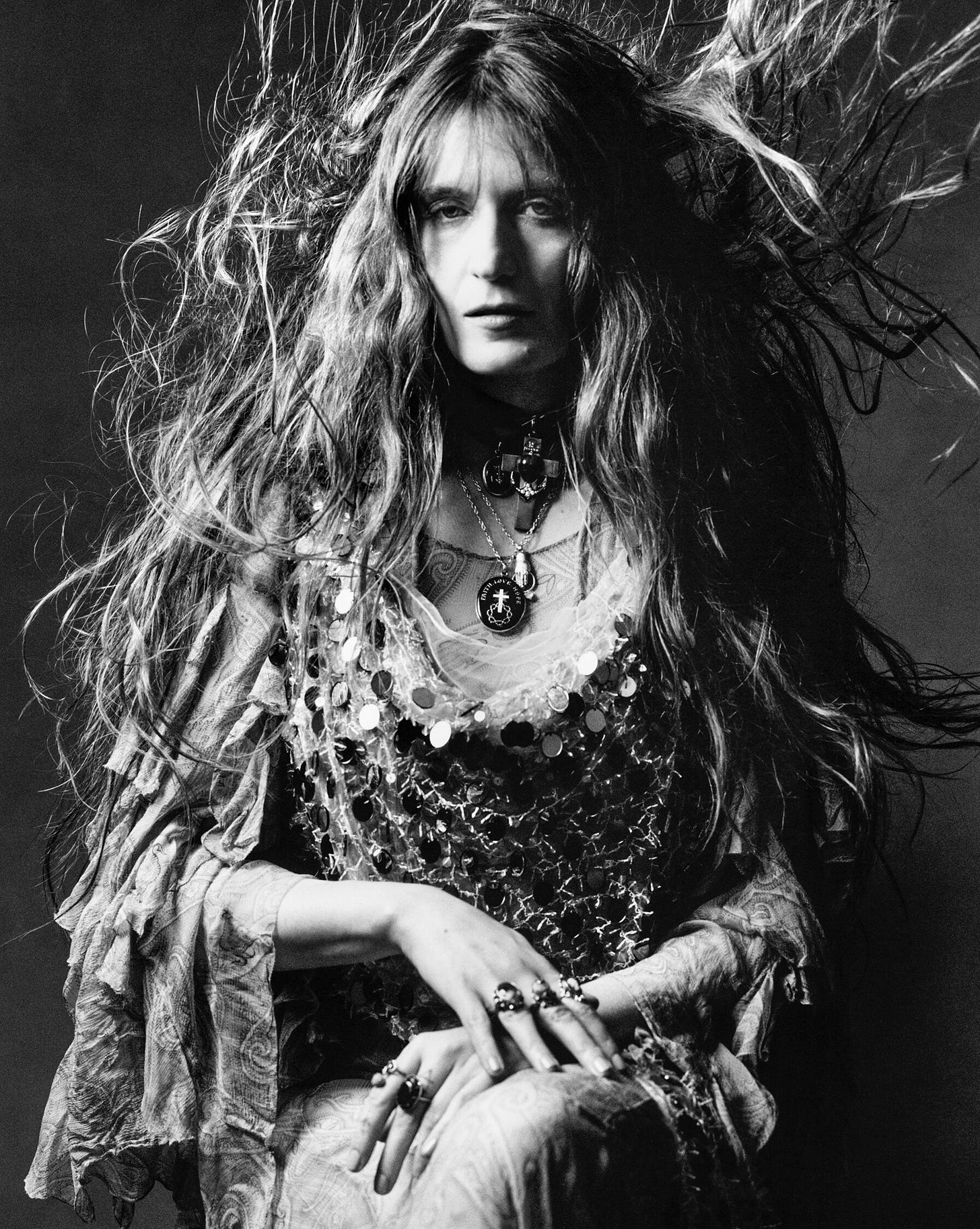 A portrait of Florence Welch wearing a sequined dress with her hair blowing in the air.