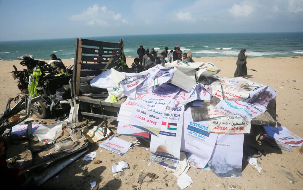 Palestinians inspect the remains of a heavily damaged humanitarian aid vehicle destroyed by Israeli airstrikes. The airstrike also killed nine Palestinians and injured dozens, in Deir al-Balah, Gaza on March 3, 2024. (Photo: Ramadan El-Agha/APA Images)