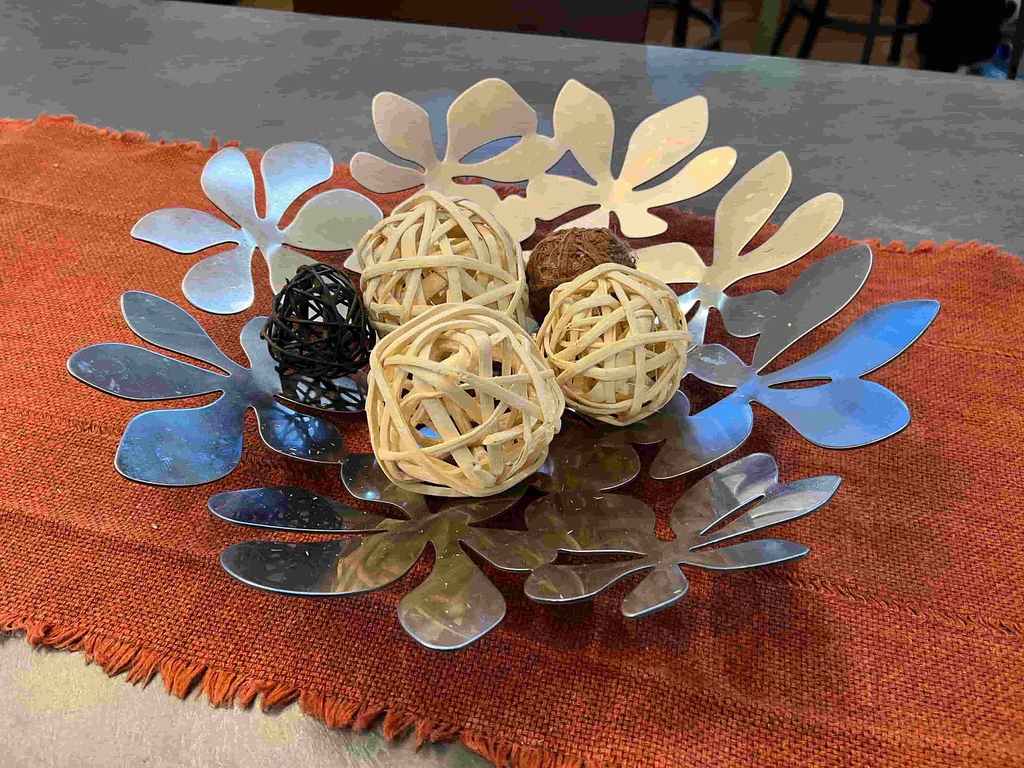 photo of wicker balls in a metal table centerpiece on an orange table runner