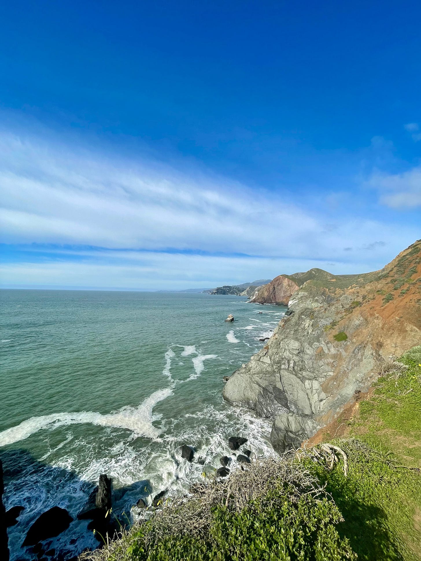 Rolling red and green cliffs that drop off into the ocean.