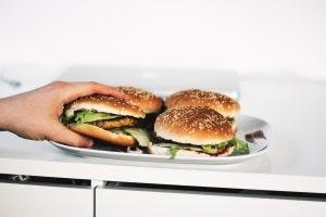 hand grabbing a burger off a plate