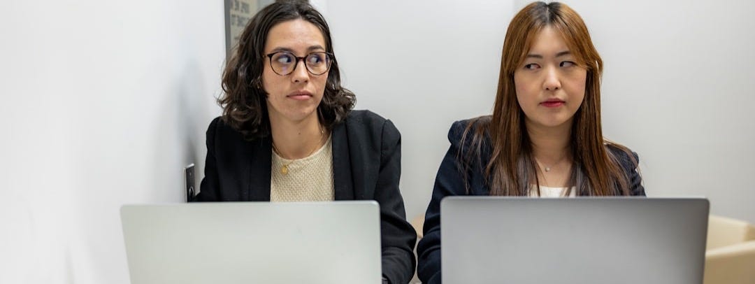 two women sitting at a table with laptops two women sitting at a table with laptops