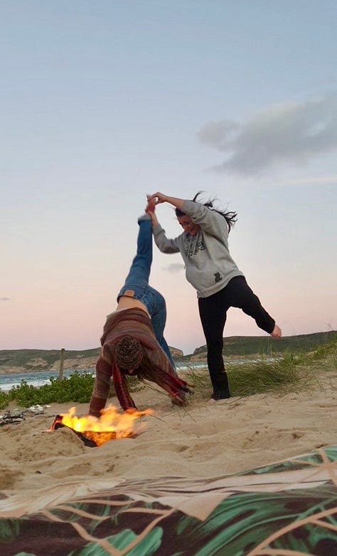 two women having fun behind a fire on the beach