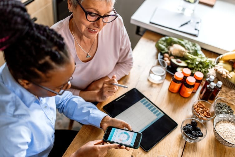 A dietician shows an older woman how to track food intake on a smartphone A dietician shows an older woman how to track food intake on a smartphone