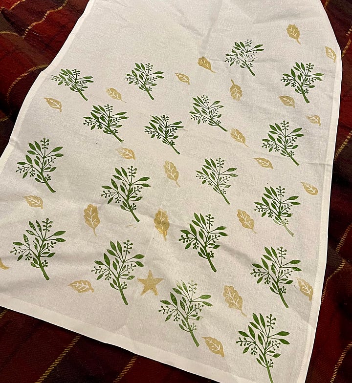 Hand-printed textiles; a tote bag with vaguely book-spine-ish pattern, the word 'BOOKS', and scattered stars; and a tea-towel with scattered green ferns and gold leaves, with one star in the melee.