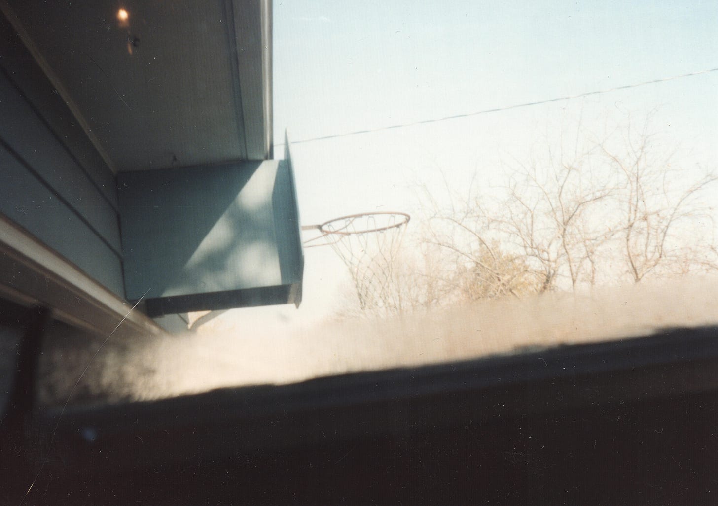 a basketball hoop photographed from inside a nearby window, crouched down very low below the window frame. 