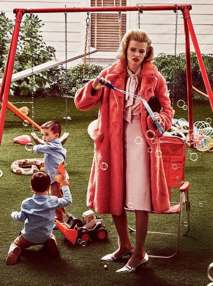 This may contain: a woman in a red coat standing next to a child on a swing with bubbles