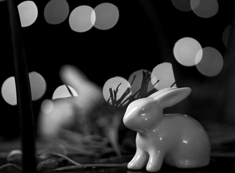a white rabbit figurine sitting on top of a table a white rabbit figurine sitting on top of a table