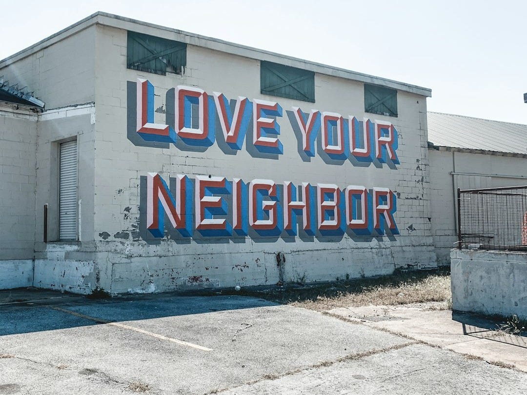 a large sign on the side of a building that says love your neighbor