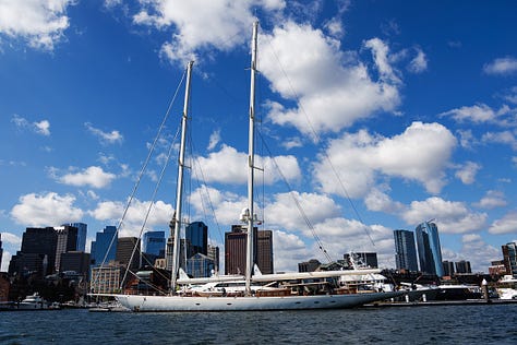 Three Boston Harbor scenes: downtown skyline, classic sailing yacht under clouds, and a dog on deck in a life vest