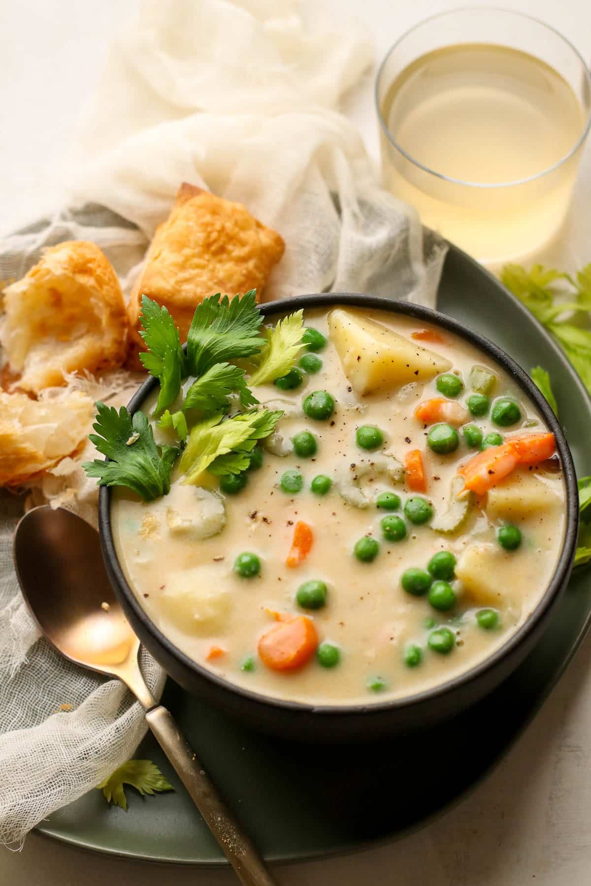 soup in a black bowl with a gold spoon and glass behind.