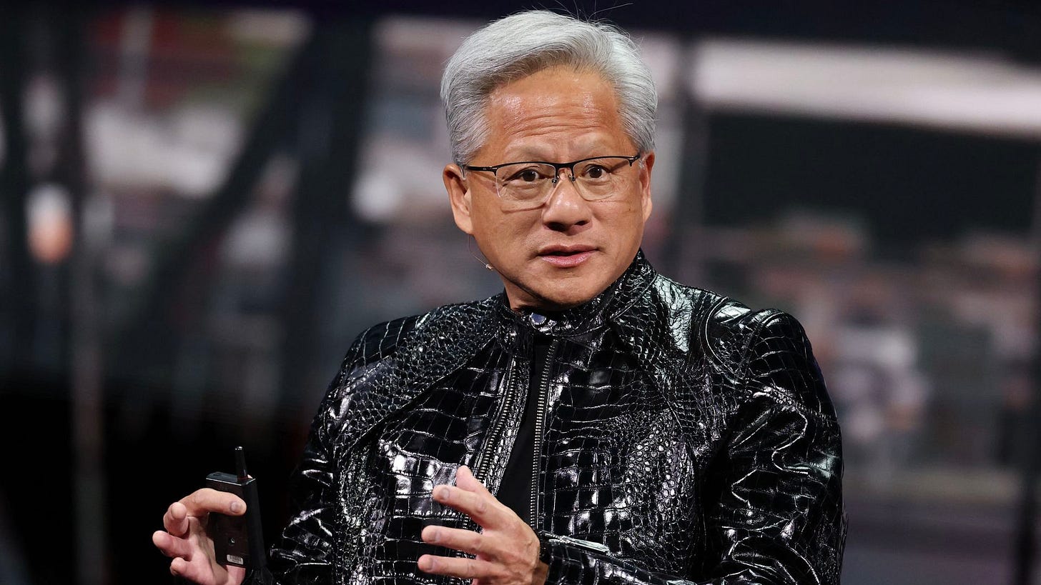 Man with glasses wearing shiny black leather jacket with out in front of him