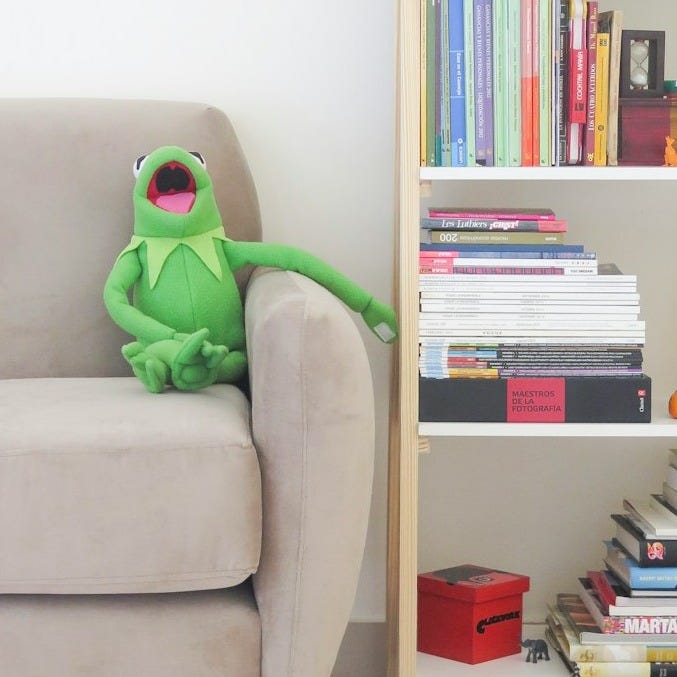 The Muppets Kermit plush toy on gray sofa