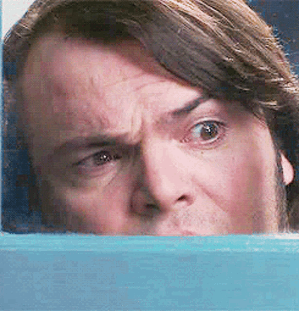 a close up of a man 's face behind a blue wall a close up of a man 's face behind a blue wall