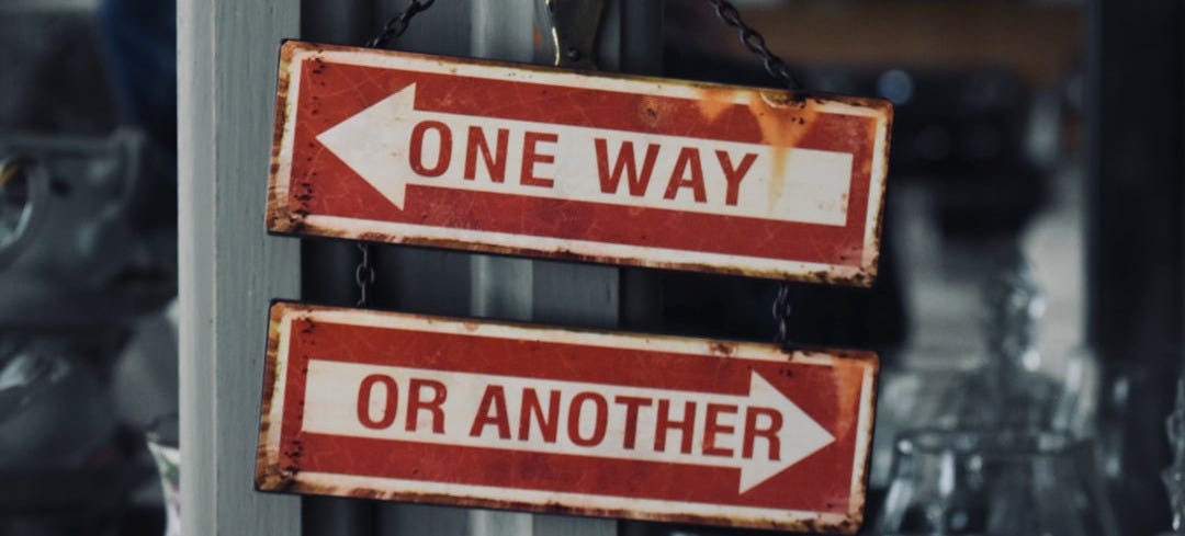 two red and white signs hanging from a metal pole