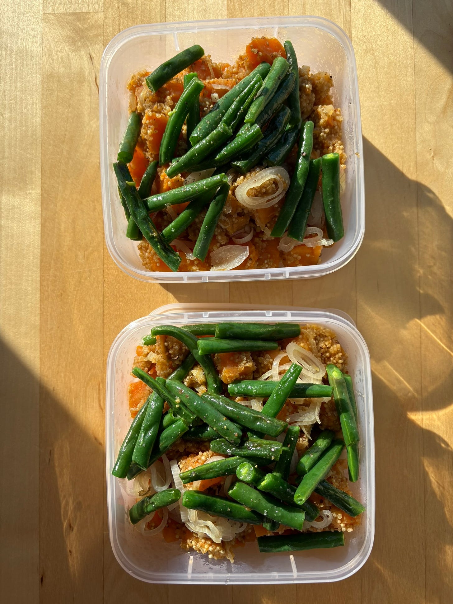 Two square takeaway containers with quinoa, sweet potato, green beans and shallots.