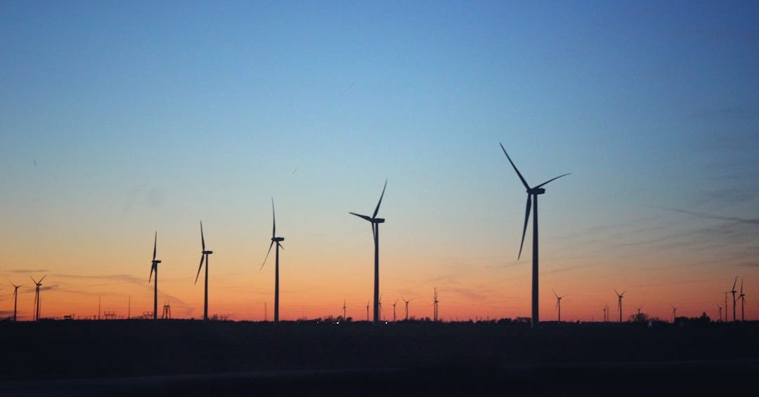 a group of windmills in a field at sunset