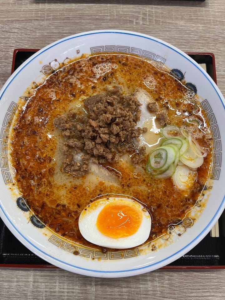 1. Meal with grilled eel on rice with miso soup on the side with raw Wagyu, tofu, chrysanthemum garlands, enoki mushrooms, and Napa cabbage on the other side for grilling. 2. A sub with beef pastrami, lettuce, and cheese drizzled with wasabi mayo on the beef. 3. Tan Tan spicy ramen with chili oil, half a soft boiled egg, and ground pork. 5. Post card of a Japanese Snow Fairy bird (Shima Enaga) on a tree branch.