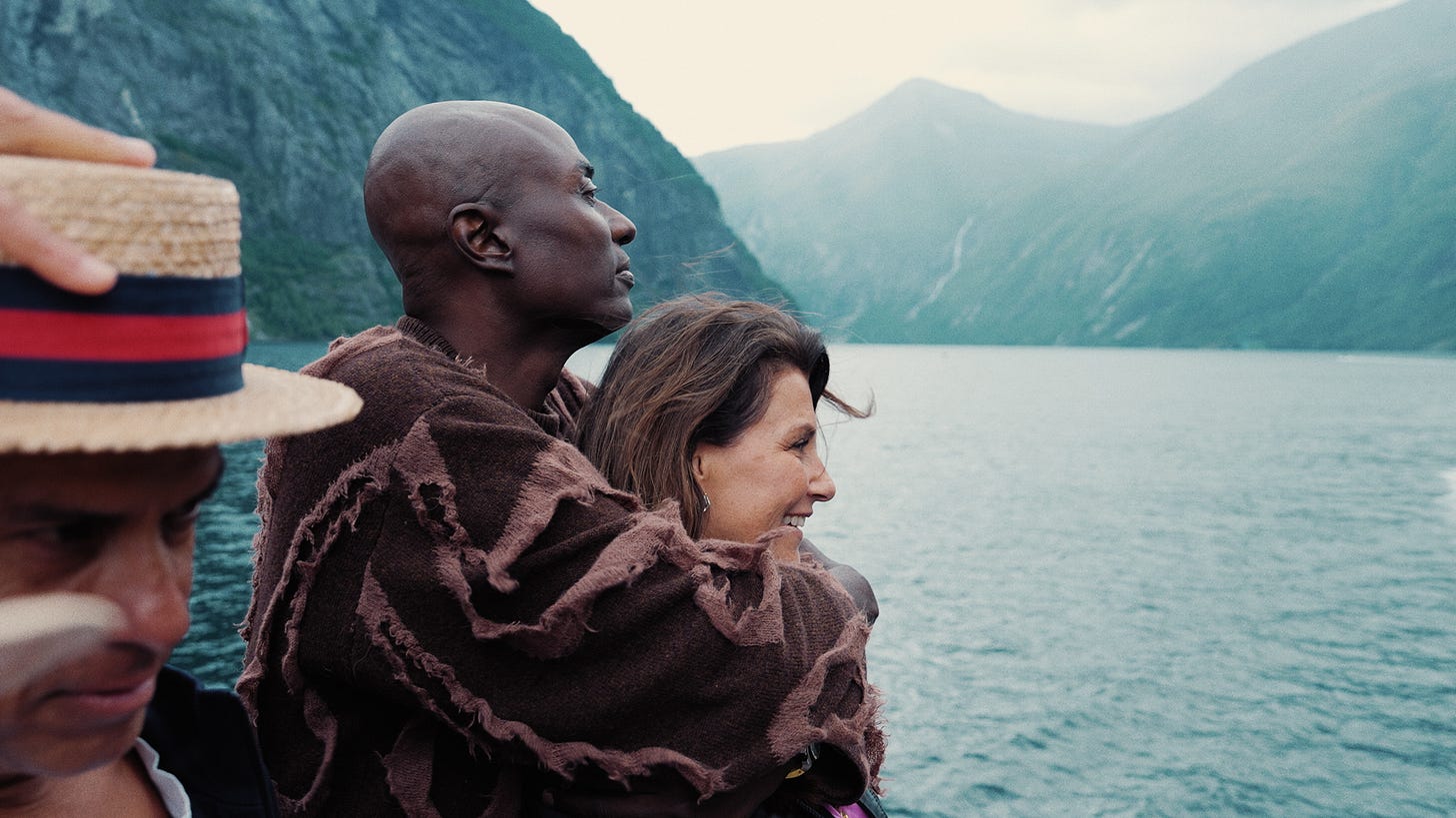 Man hugging woman on a boat on a lake with mountainous backdrop