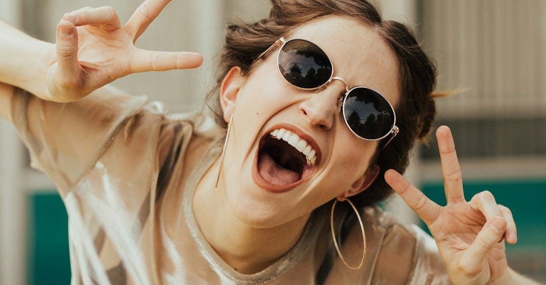 selective focus photography of jolly woman using peace hand gesture