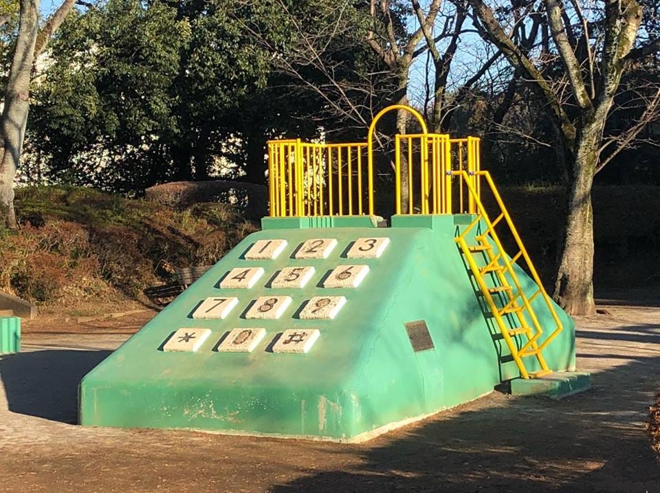 A playground slide built to resemble a giant landline telephone in chalky light green paint and yellow railings A playground slide built to resemble a giant landline telephone in chalky light green paint and yellow railings