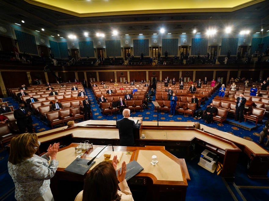 President Joe Biden addresses a joint session of Congress on the eve of his 100th day in office, as Vice President Harris and House Speaker Nancy Pelosi stand behind him on the dais.