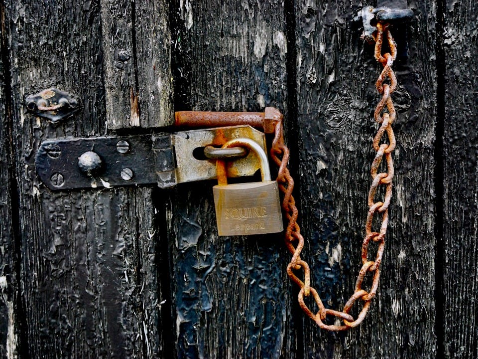 brown padlock on black wooden door brown padlock on black wooden door