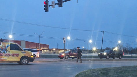 A van approaches a man crossing an intersection