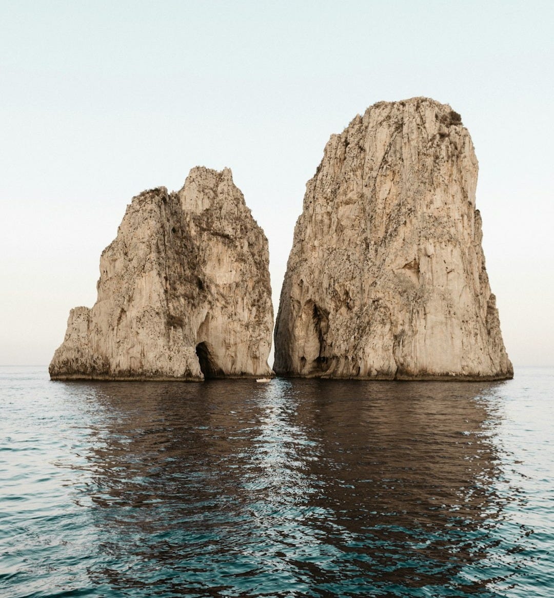 two beige rock formations on body of water