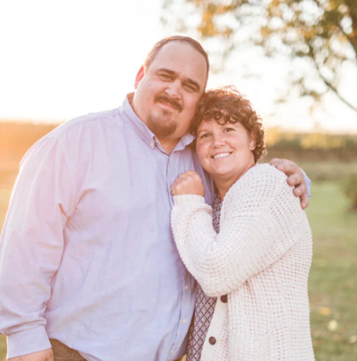 RuthAnn Zimmerman and her husband Elvin embrace outdoors in warm evening light. RuthAnn Zimmerman and her husband Elvin embrace outdoors in warm evening light.