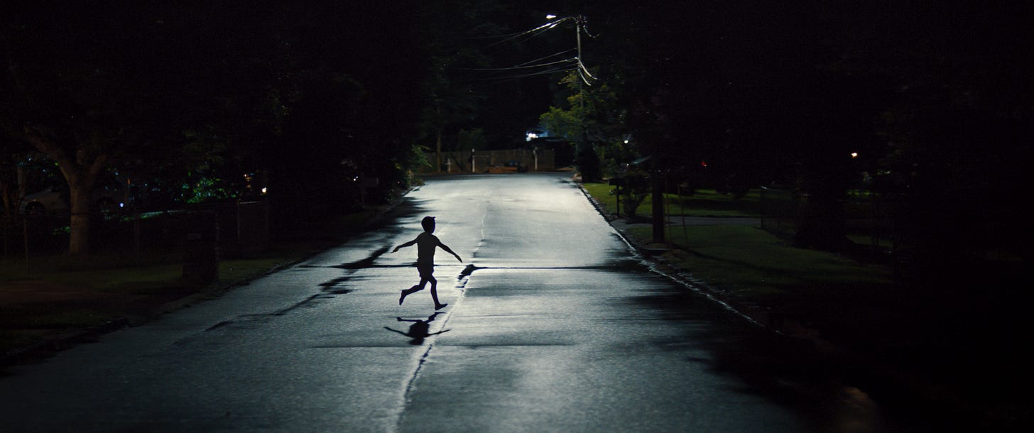 Weapons (2025) - A child runs down the road with his arms spread.