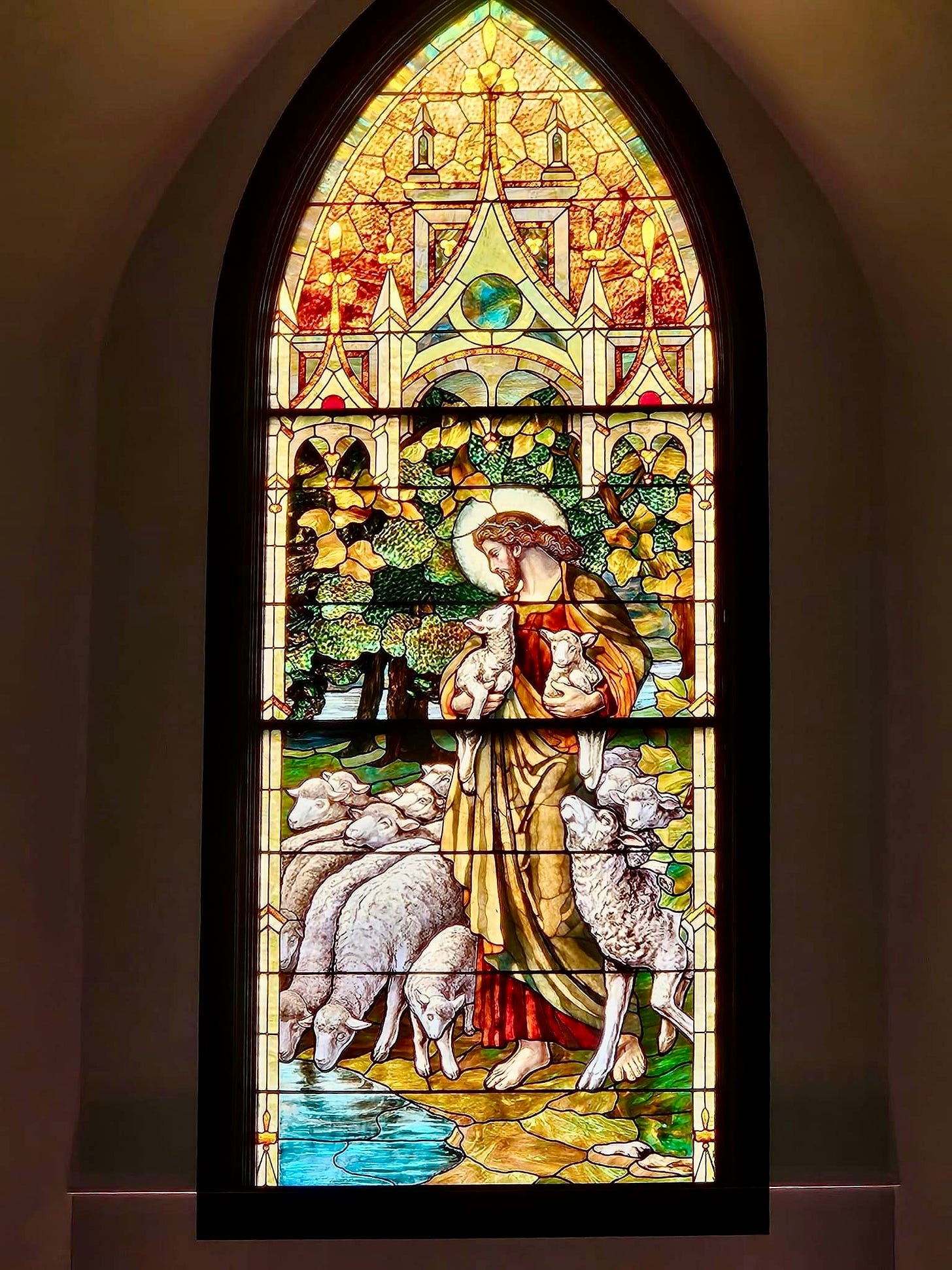 Just Come: picture of a stained glass window portraying Jesus as shepherd carrying lambs
