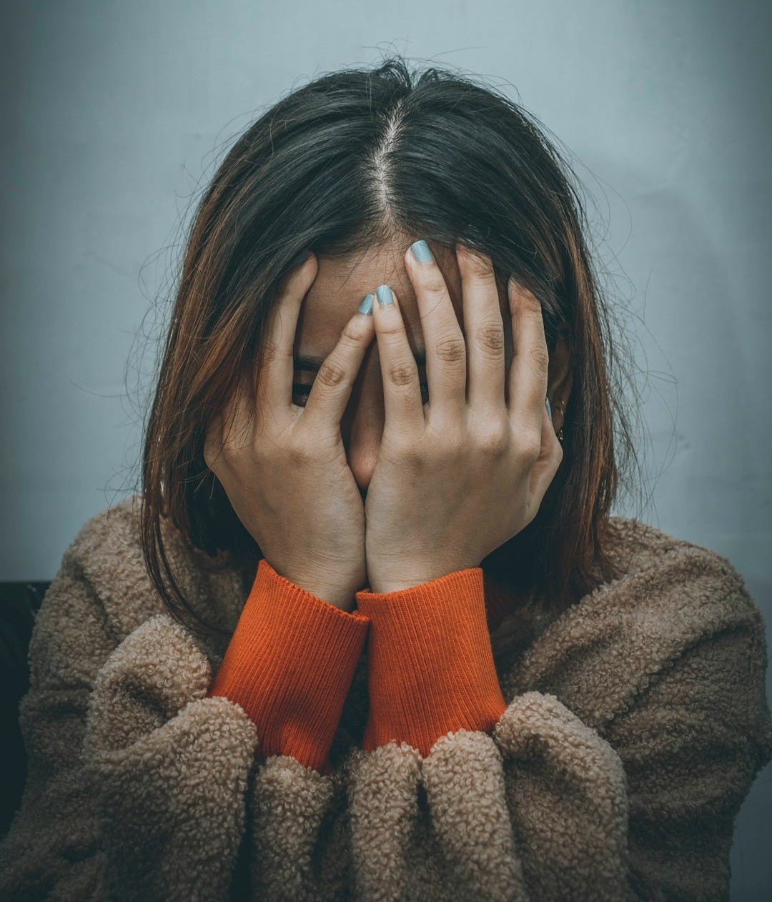 woman in brown sweater covering her face with her hand woman in brown sweater covering her face with her hand
