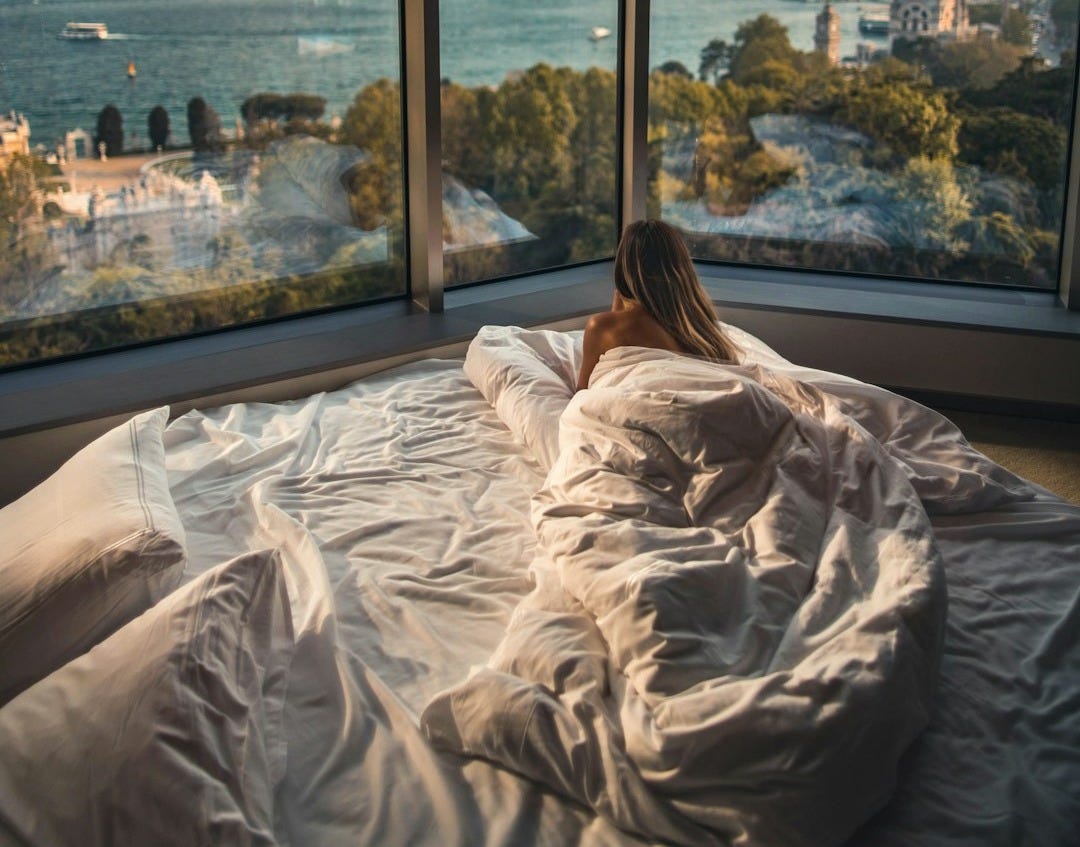 woman lying on bed facing on body of water woman lying on bed facing on body of water