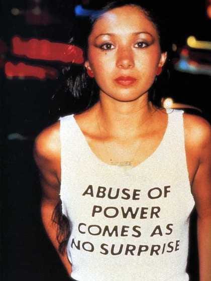 Woman wearing a white vest with the slogan 'Abuse of power comes as no surprise' Woman wearing a white vest with the slogan 'Abuse of power comes as no surprise'