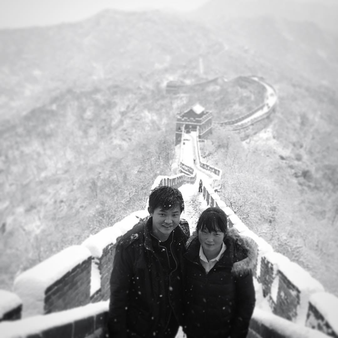 Couple poses for a photo against a snow-covered backdrop at the Great Wall's Mutianyu section.