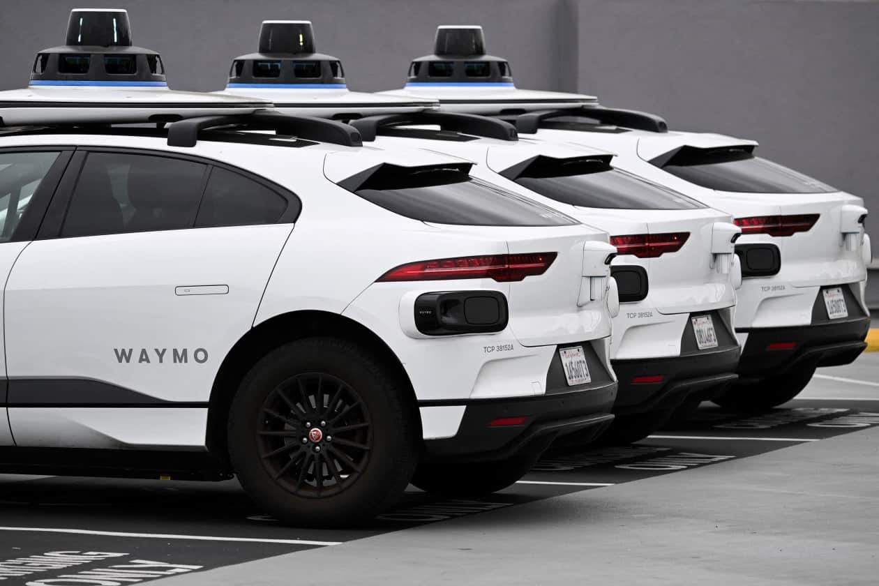 Several Waymo self-driving cars parked in a row.