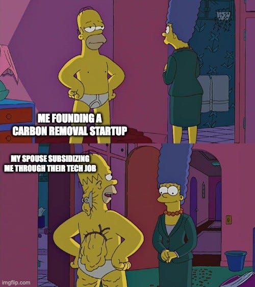 Two-panel Simpsons meme. Top: Homer stands in his underwear, hands on hips, labeled "ME FOUNDING A CARBON REMOVAL STARTUP", while Marge in a green suit walks out. Bottom: Marge, in her work suit, is labeled "MY SPOUSE SUBSIDIZING ME THROUGH THEIR TECH JOB" as Homer stands by in his underwear.