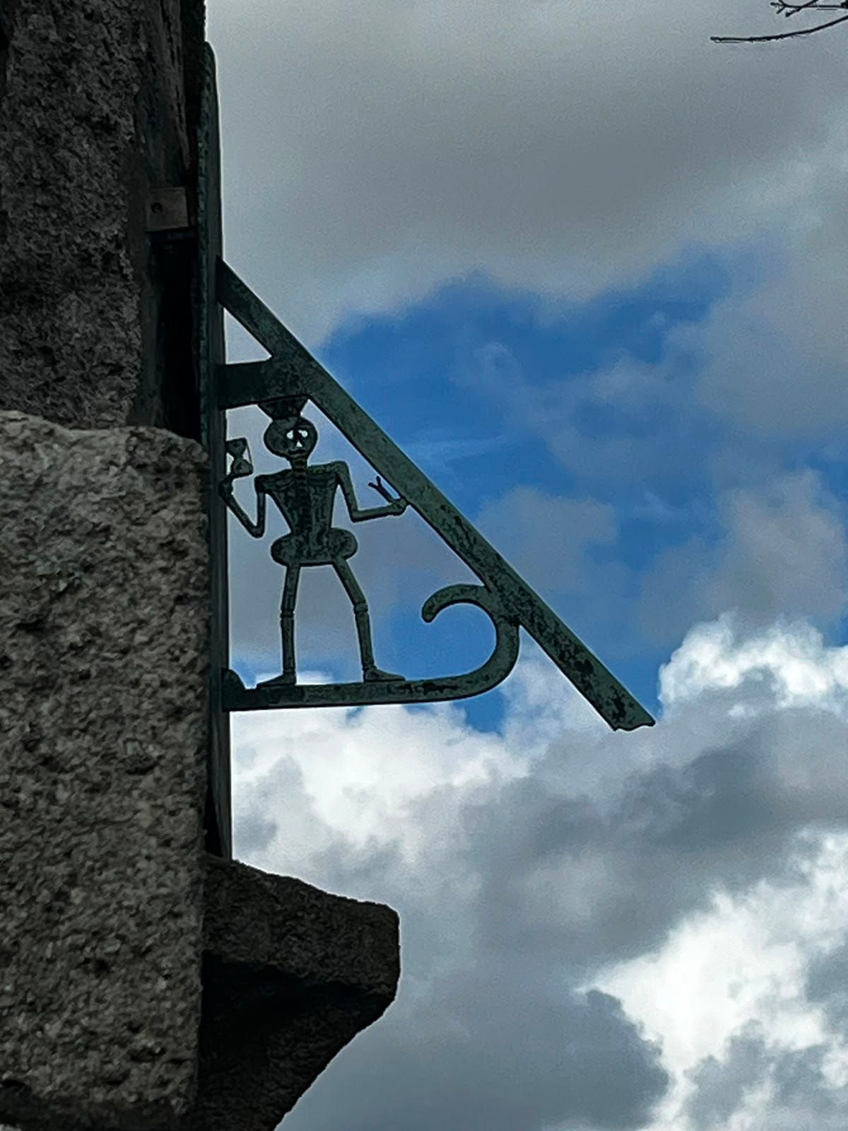 The sundial above the church porch: a skeleton holding an hourglass The sundial above the church porch: a skeleton holding an hourglass