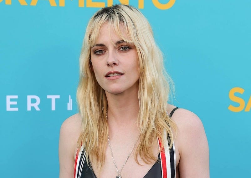 kristen stewart on a red carpet with blonde hair and dark roots