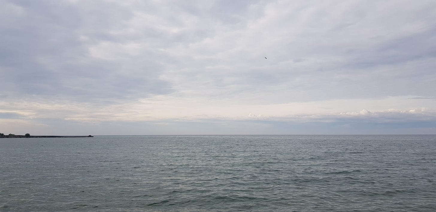灰色調的開闊湖面與多雲天空,遠處一道平靜的地平線。 灰色調的開闊湖面與多雲天空,遠處一道平靜的地平線。