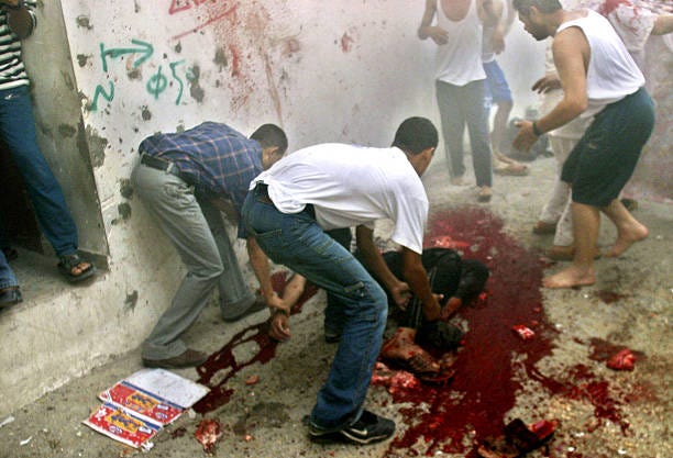 Palestinians remove the body of a explosion victim August 3, 2004 in Rafah, Gaza Strip. An explosion killed three Palestinians and wounded 16 others...
