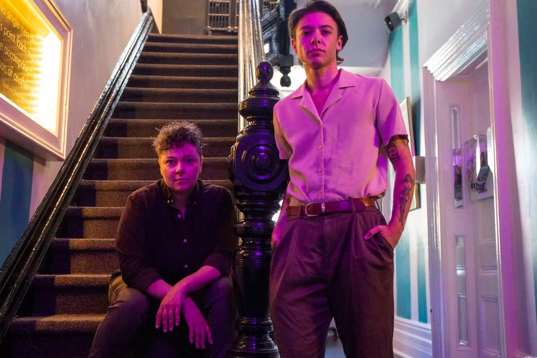 Project manager Alisha Stranges and oral historian Elio Colavito of the Pussy Palace Oral History Project next to an original staircase from the former site of the Pussy Palace bathhouse for women and transgender people, now the Oasis Aqualounge.