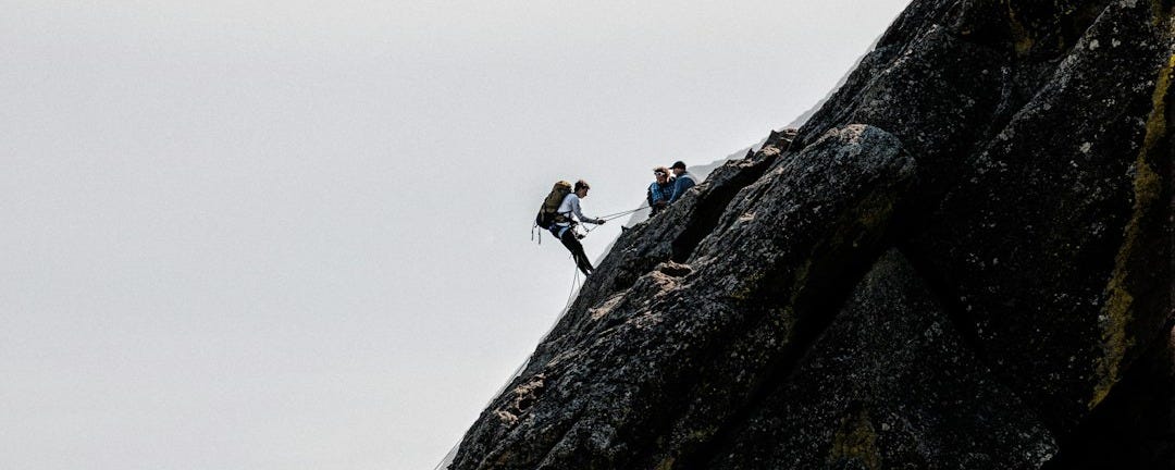 2 person climbing on rocky mountain during daytime